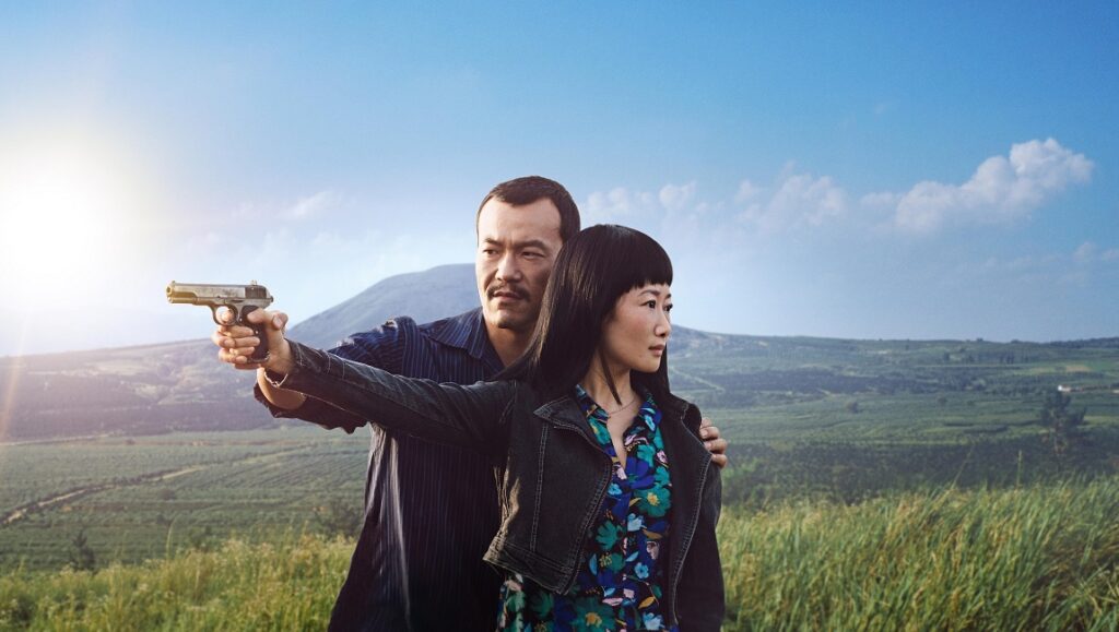 Ash is Purest White film still. A man points a gun as a woman stands beside him in a field. Jia Zhangke movie.