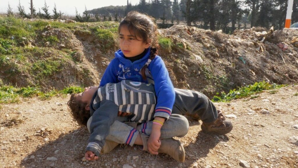 Bitter Bread | Abbas Fahdel Bitter Bread image: Child comforts another in a field. Abbas Fahdel film still. Poverty and hardship.