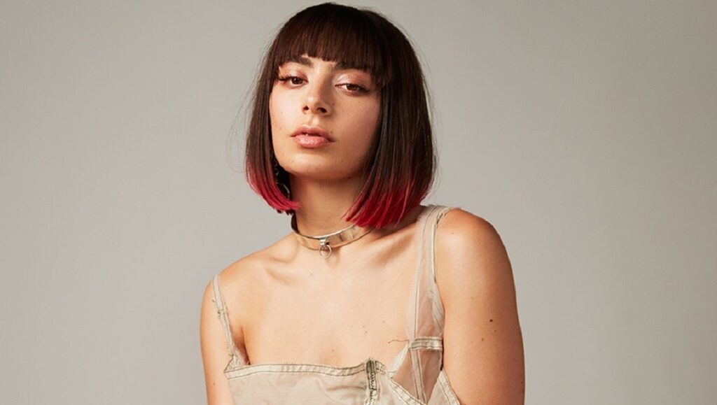 Charli XCX | How I’m Feeling Now Charli XCX portrait. Singer with blunt bangs, bob haircut with red tips, and a silver collar. How I'm Feeling Now era.