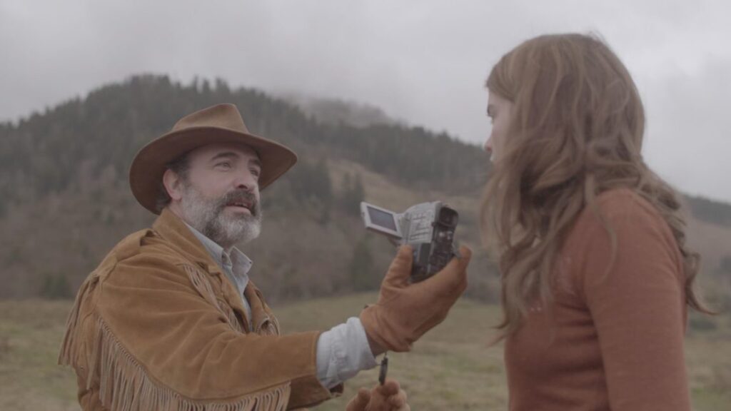 Deerskin movie scene. Man in deerskin jacket films woman with camera. Quentin Dupieux film.