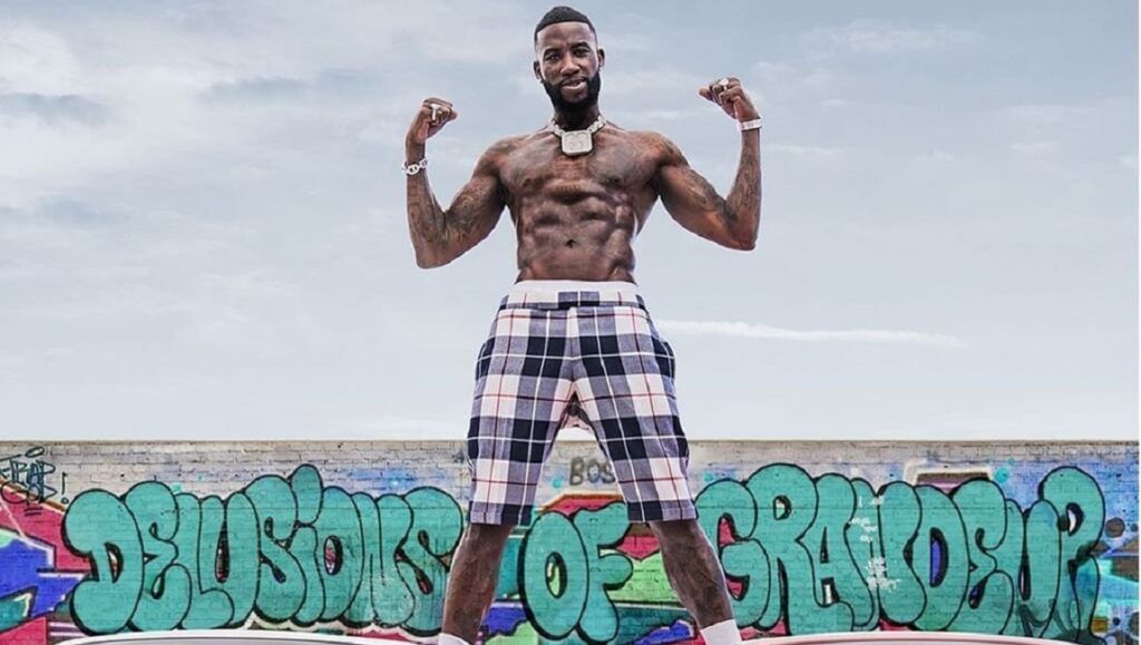 Gucci Mane | Delusions of Grandeur Gucci Mane 'Delusions of Grandeur' album art. Rapper flexing abs in front of graffiti.