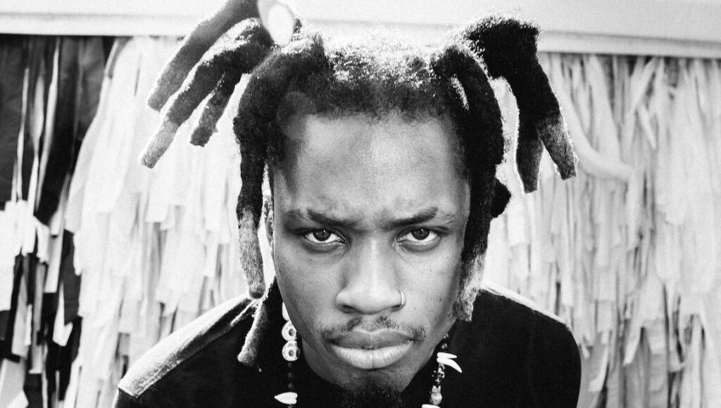 Denzel Curry | Zuu Denzel Curry, Zuu album era. Black and white portrait of the rapper with dreadlocks and jewelry.