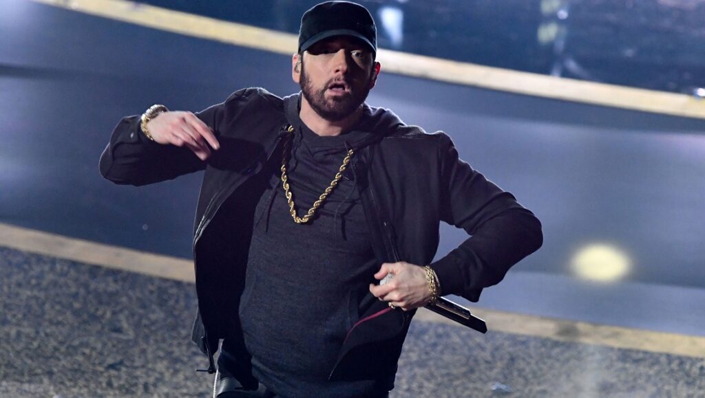 Eminem performing Music to Be Murdered By. Rapper with gold chain and microphone.