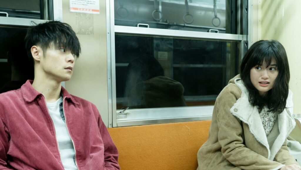 First Love | Takashi Miike First Love film scene: Two young characters on a train, looking concerned.