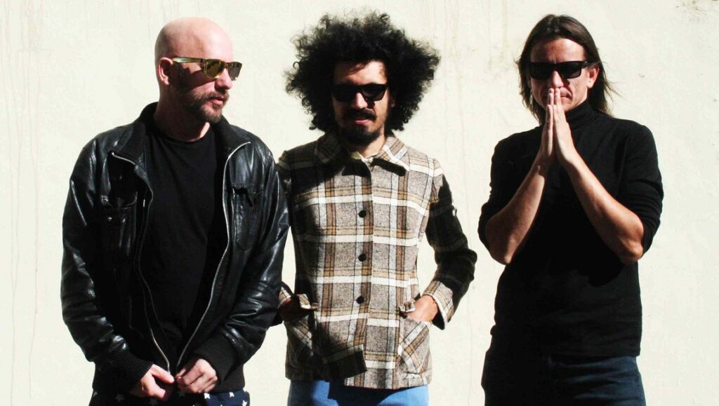 Fumaça Preta | Pepas Fumaça Preta band members. Pepas album art. Rock band promo. Bald man, afro, and long hair. Sunglasses.