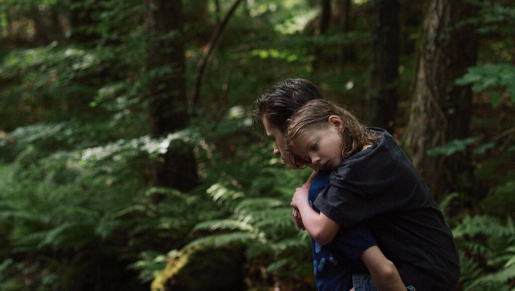 I Was at Home, But... film still: Angela Schanelec movie scene of a man carrying a child in a forest.