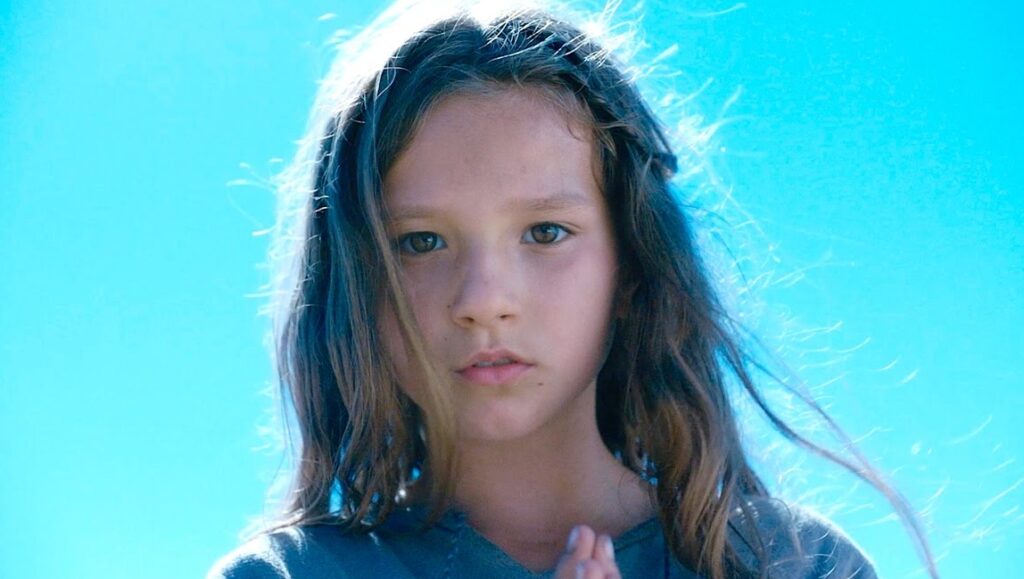 Jeannette: The Childhood of Joan of Arc. Young girl with long hair against a bright blue sky. Film still.