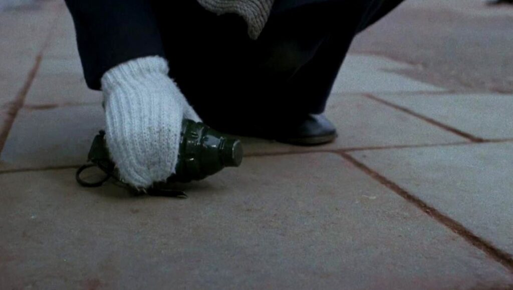 Frank Beauvais' Just Don't Think I'll Scream film still: A hand in a glove holds a grenade on a stone surface.