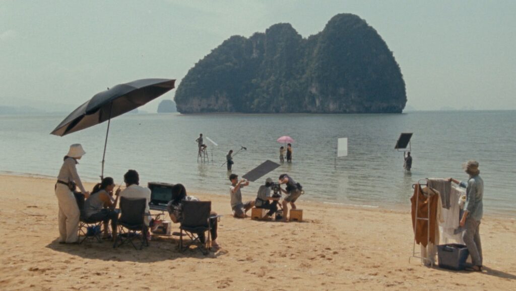 Film crew on Krabi beach, Thailand. Island backdrop, cast in water. Anocha Suwichakornpong & Ben Rivers film.