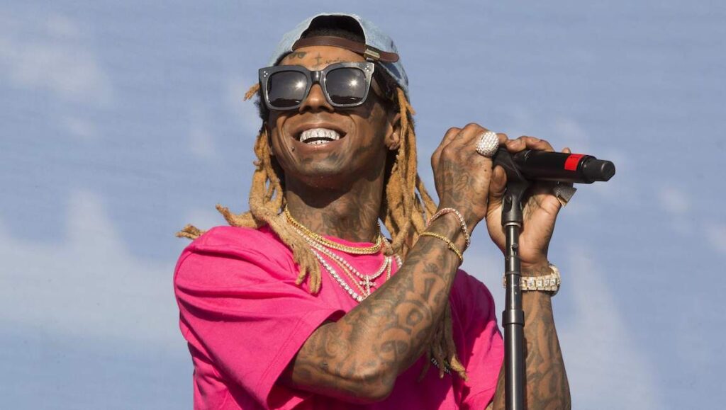 Lil Wayne| Tha Carter V Lil Wayne performing Tha Carter V. Rapper with dreadlocks, sunglasses, and tattoos holding a microphone.