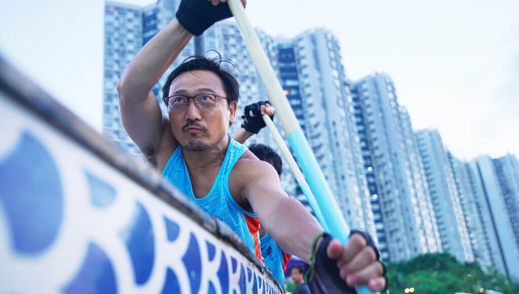 Men on the Dragon boat race. Teamwork, paddling in sync. Sunny Chan's dragon boat team competes. Hong Kong sport.