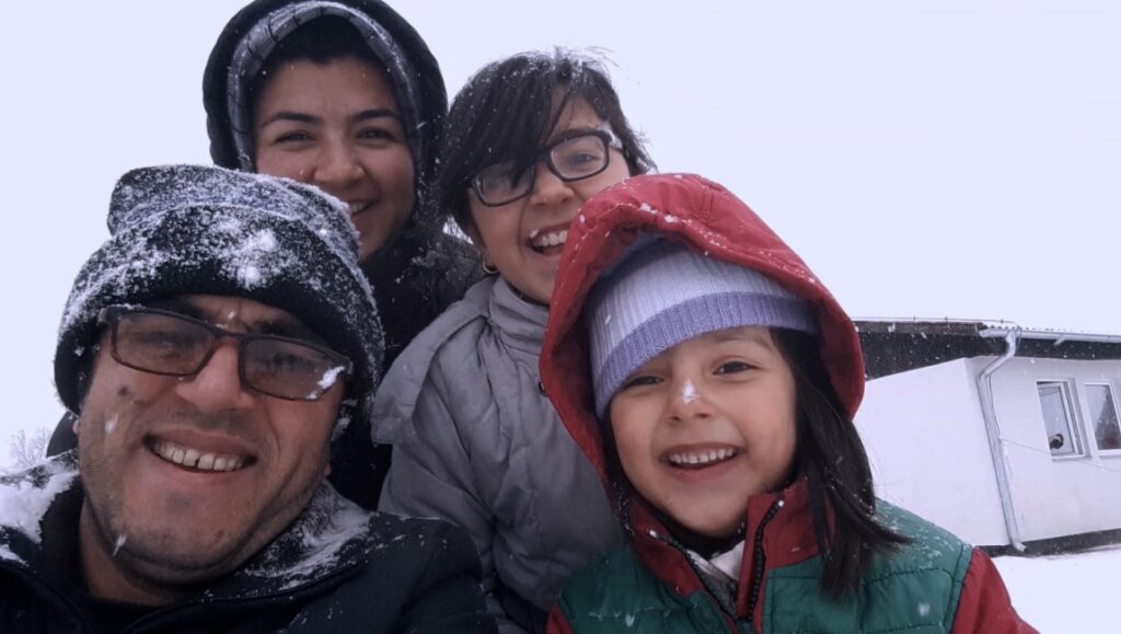 Midnight Traveler | Hassan Fazili & Fatima Hussaini Midnight Traveler film: Hassan Fazili, Fatima Hussaini, and family smiling in the snow.