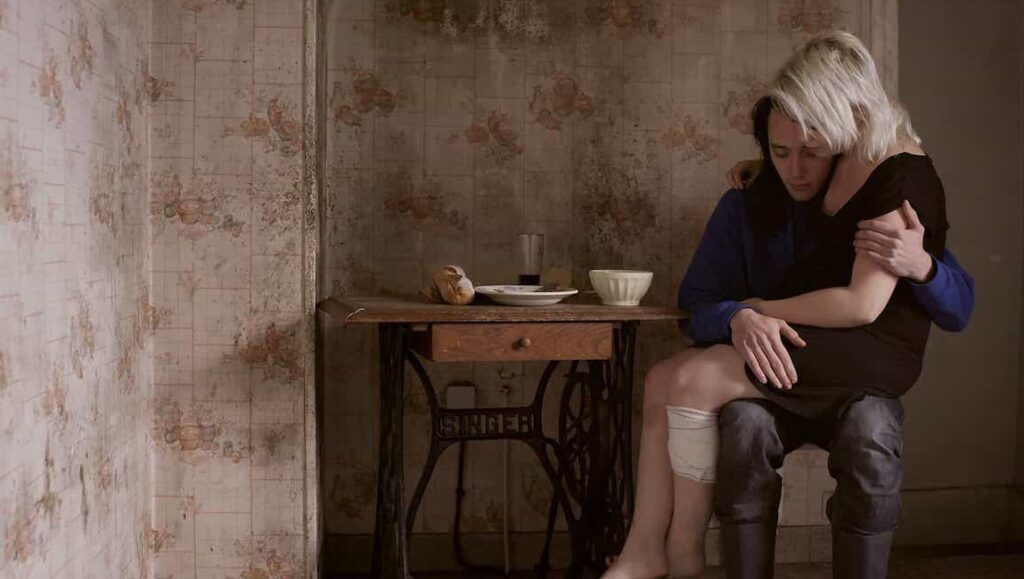 Milla film still: Valérie Massadian's Milla, depicting a couple in a tender embrace in a rustic interior.