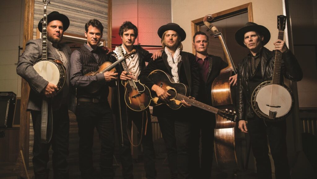 Old Crow Medicine Show performing live at the Ryman. Band members with banjo, fiddle, guitar, and bass.