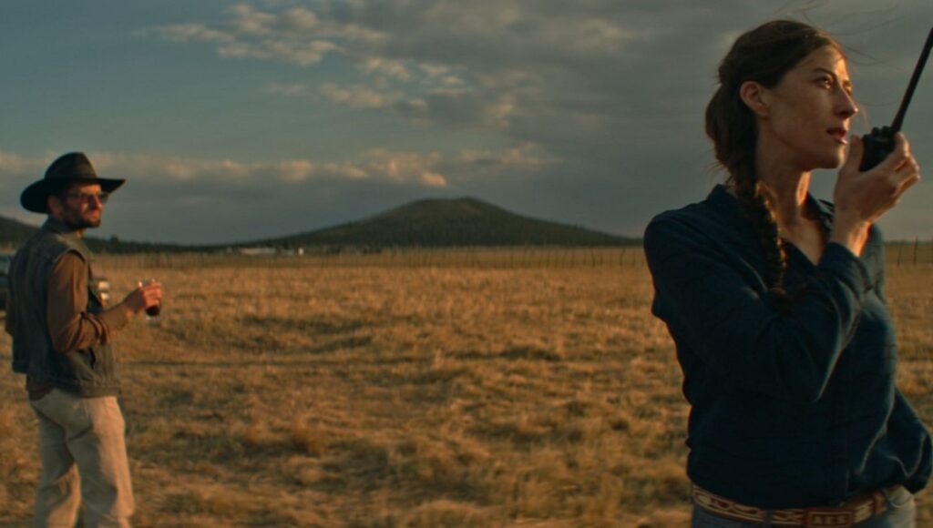 Our Time movie still. Woman with walkie-talkie, man with hat in field. Carlos Reygadas film.