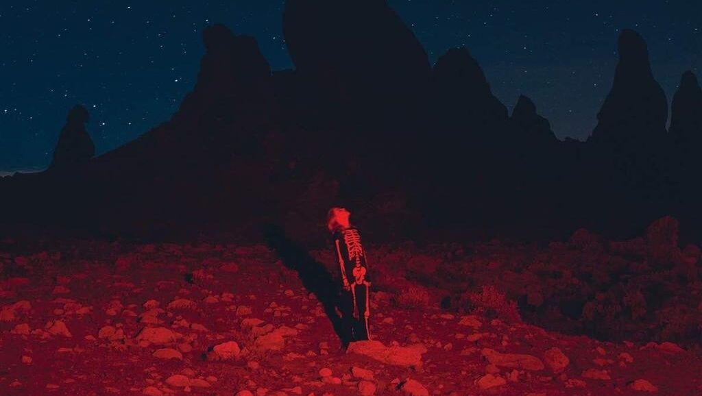 Phoebe Bridgers | Punisher Phoebe Bridgers album cover. Skeleton figure in red light, desert landscape, starry night. Arca, Yves Tumor.
