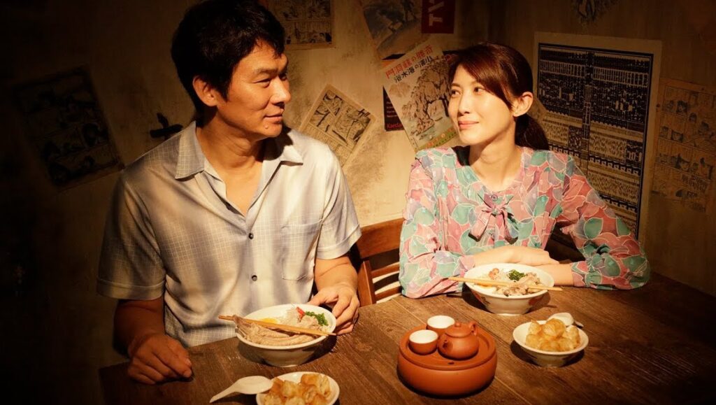 Ramen Shop | Eric Khoo Ramen Shop film scene: A man and woman enjoy ramen at a table. Teapot and fried dough on the wooden table.