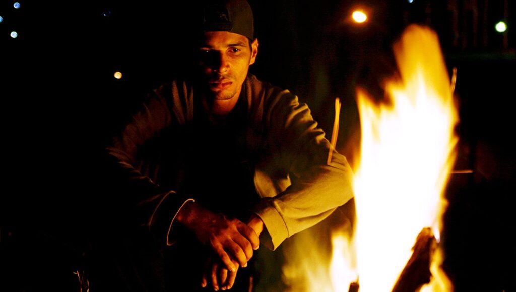 Seven Years in May | Affonso Uchôa Affonso Uchôa's Seven Years in May film still. Man by campfire, dark, contemplative.