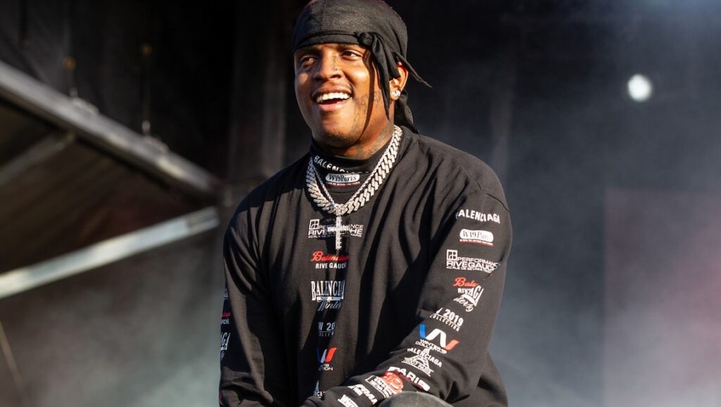 Ski Mask the Slump God | Stokeley Ski Mask the Slump God, also known as Stokeley, smiles wearing a black bandana and a cross necklace.