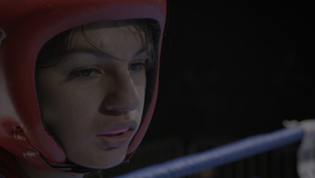 Strike or Die | Jonathan Rescigno Jonathan Rescigno's Strike or Die: Boxer in red headgear, intense gaze. Boxing ring ropes visible.