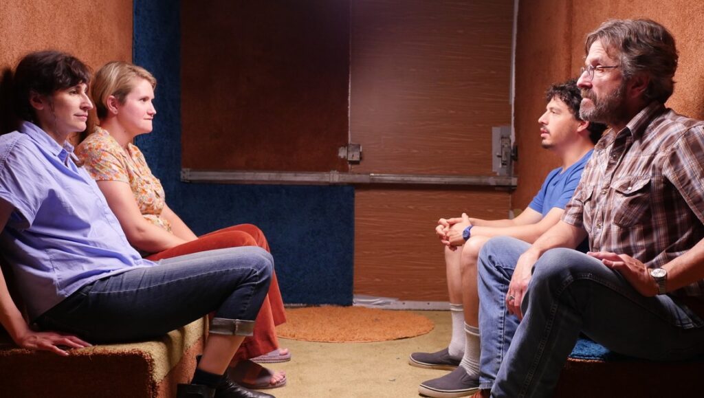 Sword of Trust | Lynn Shelton Sword of Trust film still. Four people sit facing each other in a small room. Marc Maron stars in Lynn Shelton's comedy.