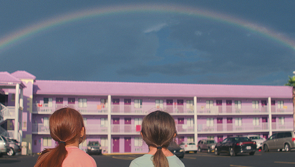 Two girls look at a rainbow over a purple motel in The Florida Project movie.