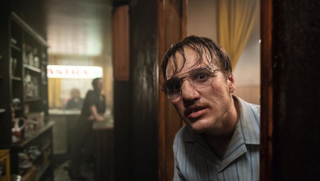 The Golden Glove | Fatih Akin The Golden Glove movie still. Man with glasses peers from doorway of bar. Fatih Akin film.