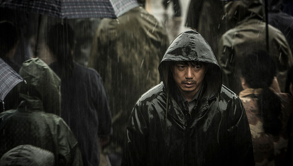 The Looming Storm | Dong Yue Dong Yue's The Looming Storm film still. Man in a hooded raincoat in the rain.