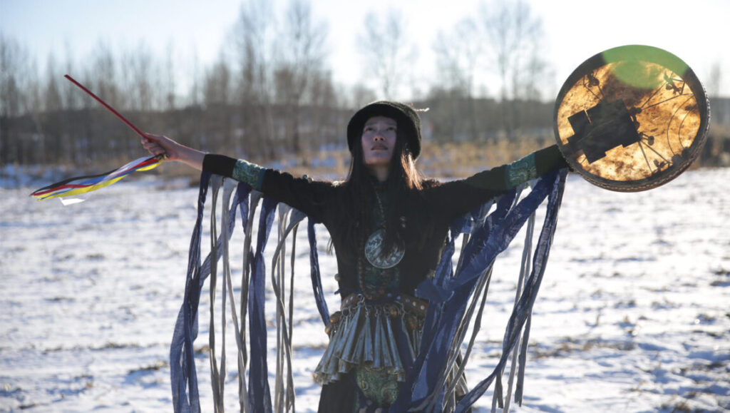 Cai Chengjie's The Widowed Witch: A shamanic ritual in a snowy landscape. Woman with drum and ribbons, spiritual performance art.