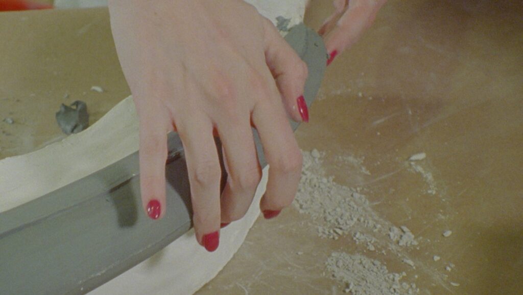 Jessica Sarah Rinland artwork: Hands shape clay with a tool. Art installation detail from Those That, at a Distance, Resemble Another.