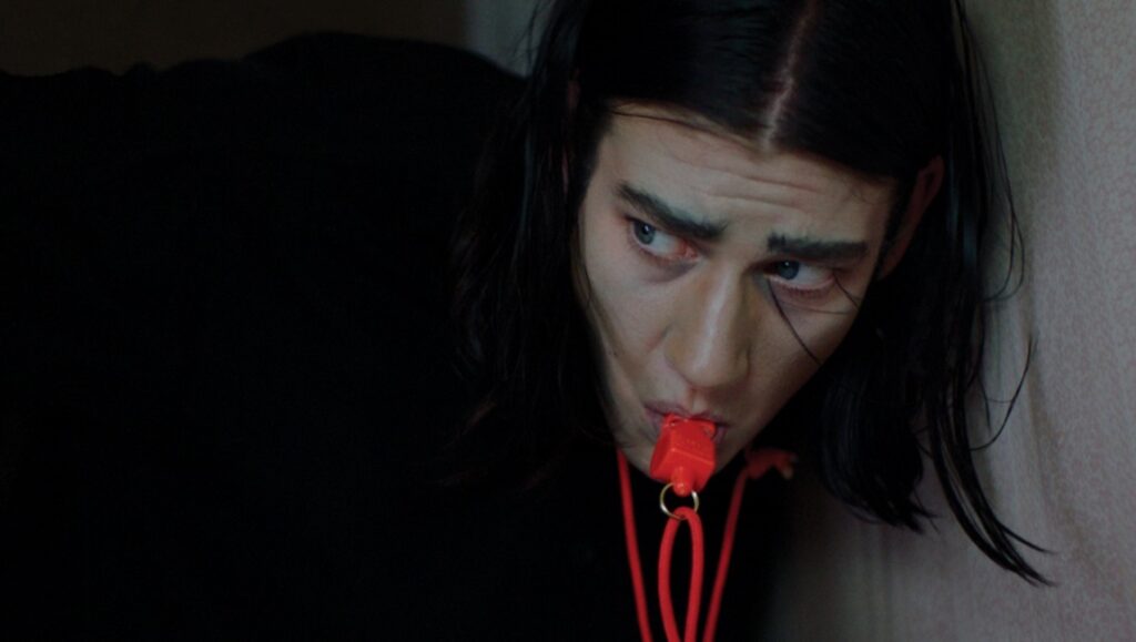 Before We Vanish film still: Man with long black hair blowing a whistle. July 2020 movie review.