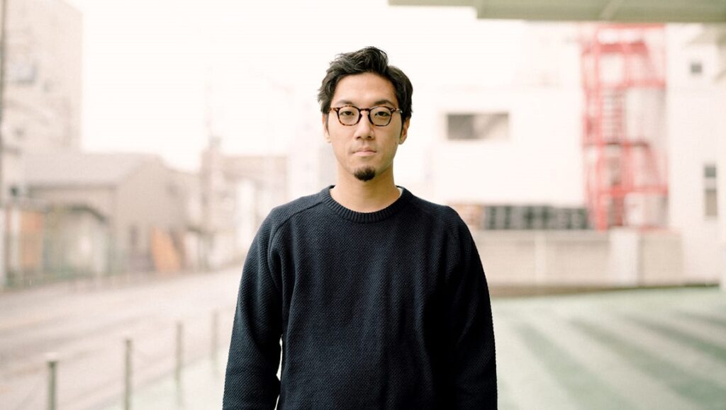 Tofubeats | Run Tofubeats portrait. Japanese musician Tofubeats wears glasses and a dark sweater. Run music video.