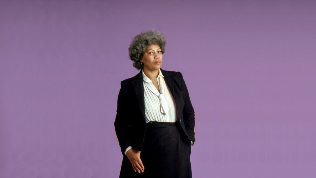 Toni Morrison portrait. Author in black suit against a purple background. Toni Morrison: The Pieces I Am.