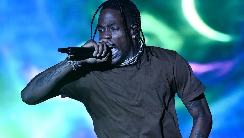 Travis Scott performing live. Rapper with braids singing into a microphone during Astroworld concert.