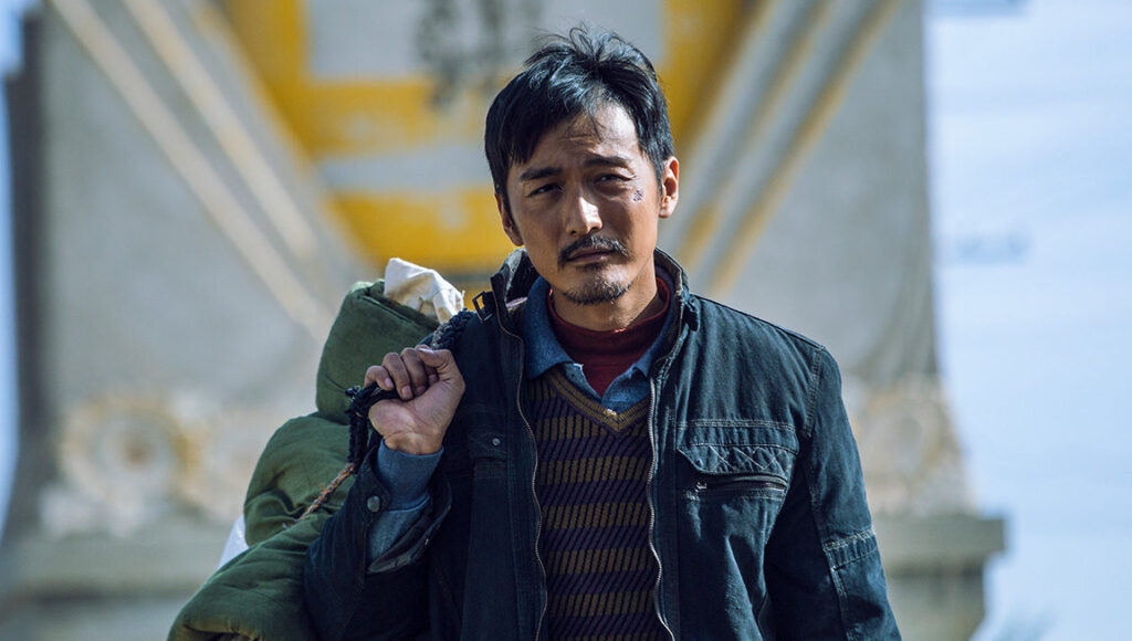 Wrath of Silence | Xin Yukun Wrath of Silence film still. Xin Yukun directs a man with a determined expression, carrying a bag.