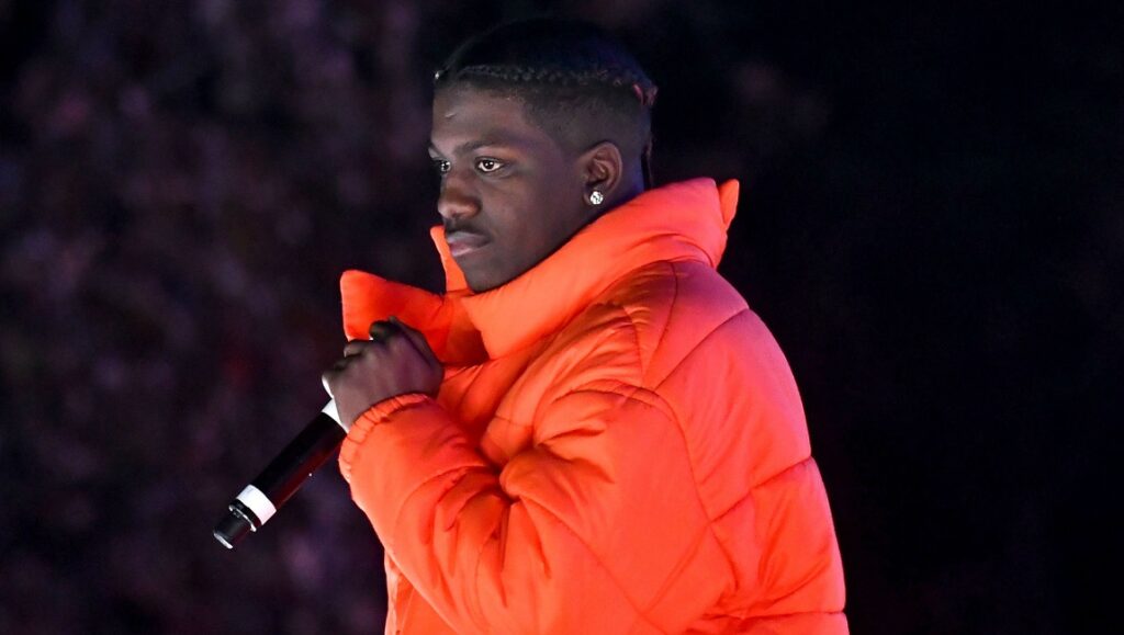 Lil Yachty, Lil Boat 3 era. Rapper in orange puffer jacket holding a microphone.