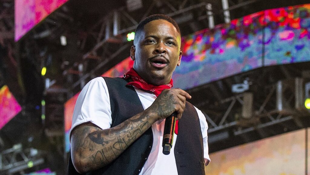 YG | 4Real 4Real YG performing live. Rapper YG on stage for 4Real 4Real album. Red bandana, tattoos, and microphone.