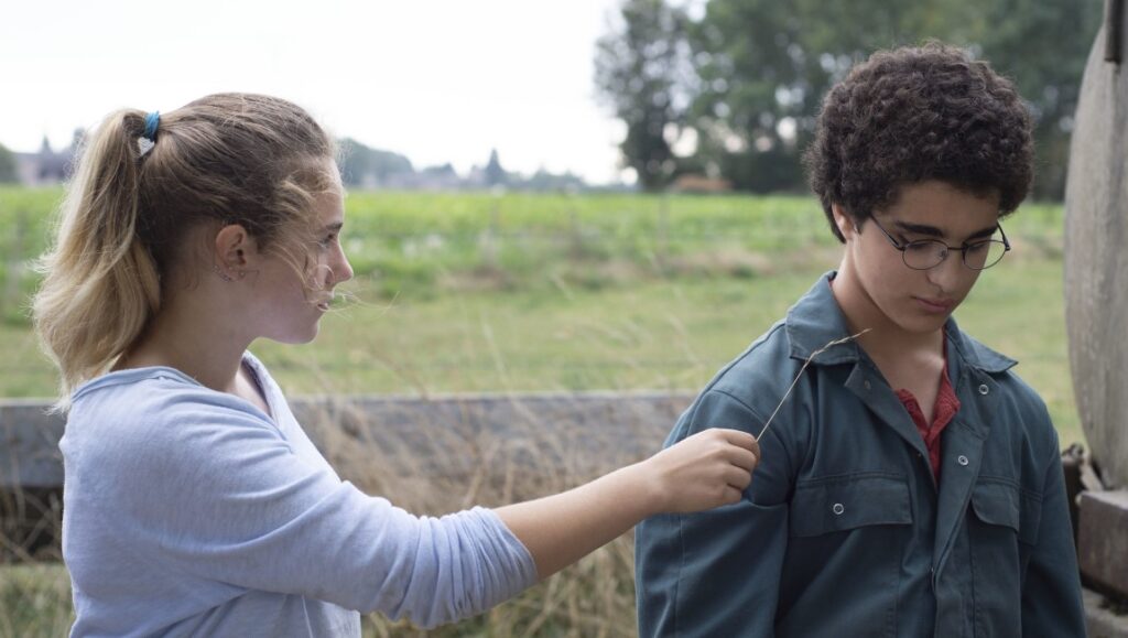 Young Ahmed movie scene. Girl teases Ahmed with grass. Jean-Pierre and Luc Dardenne film.