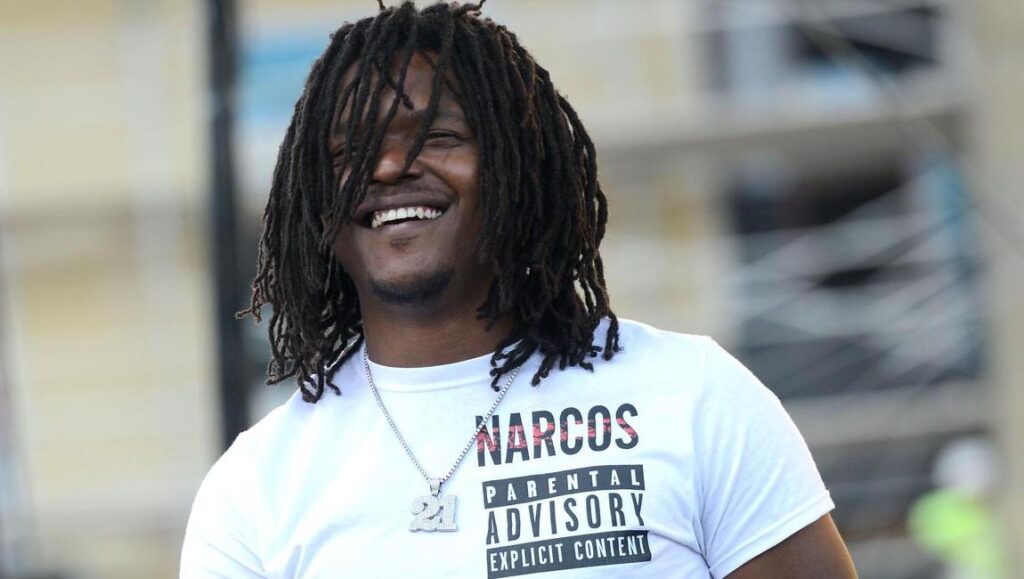 Young Nudy | Sli’merre Young Nudy smiling. Rapper with dreadlocks wearing a Narcos parental advisory t-shirt. Sli'merre album.