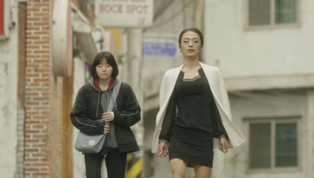 Cho Hyun-hoon's Jane film still. Two women walk down a street. One wears a dress and blazer.