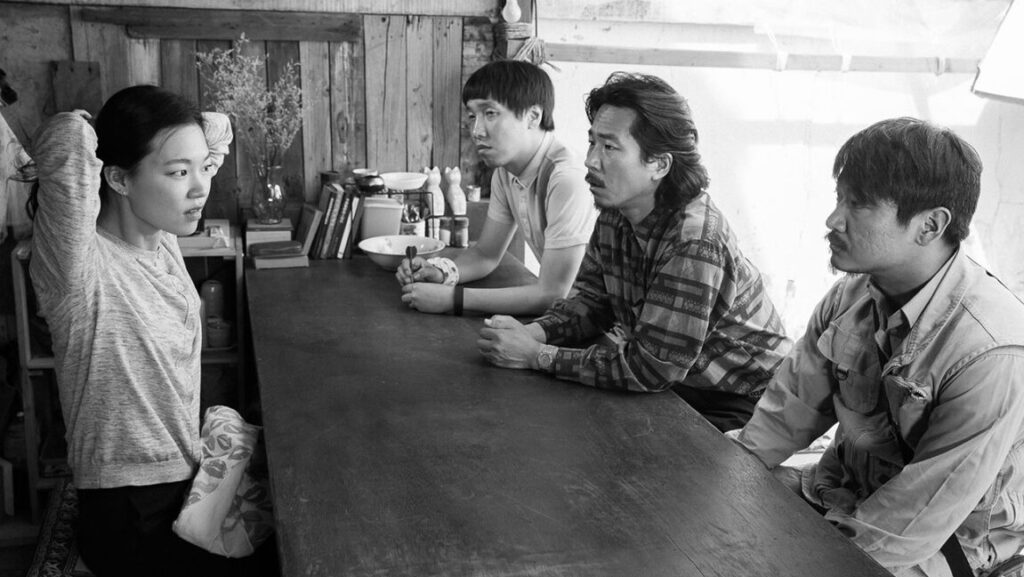 A Quiet Dream film scene: Woman and three men at a table. Black and white.