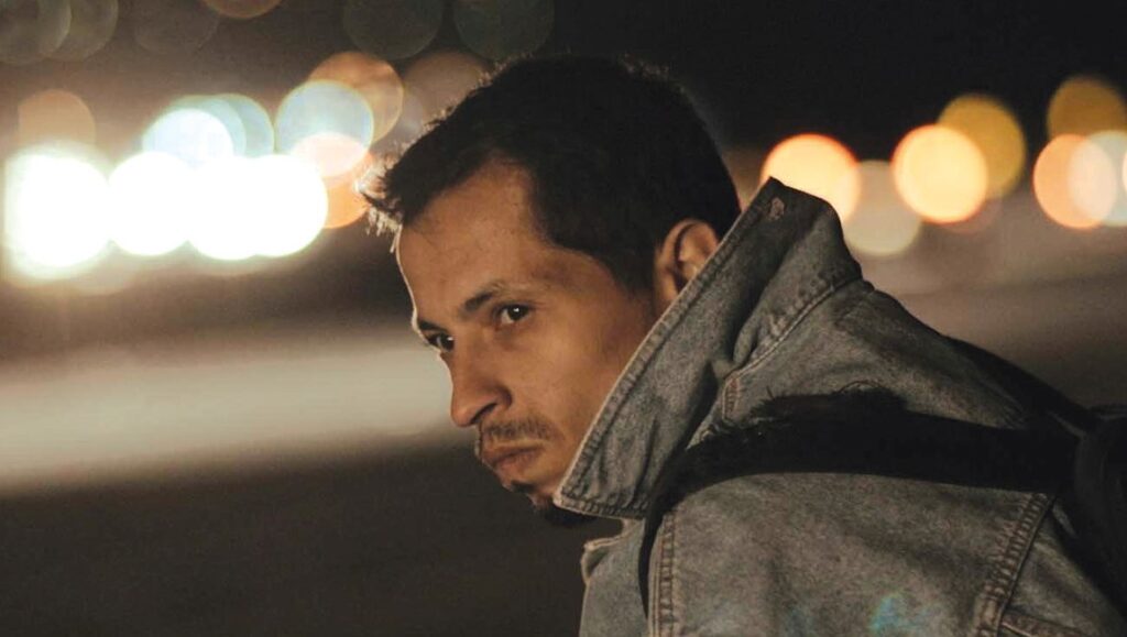 Araby | João Dumans & Affonso Uchoa Araby film still: Man in denim jacket looks to the side at night.