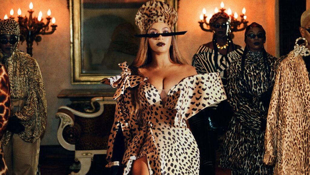 Black is King | Beyonce Beyonce in Black is King wearing a leopard print dress and sunglasses, surrounded by people in animal print outfits.
