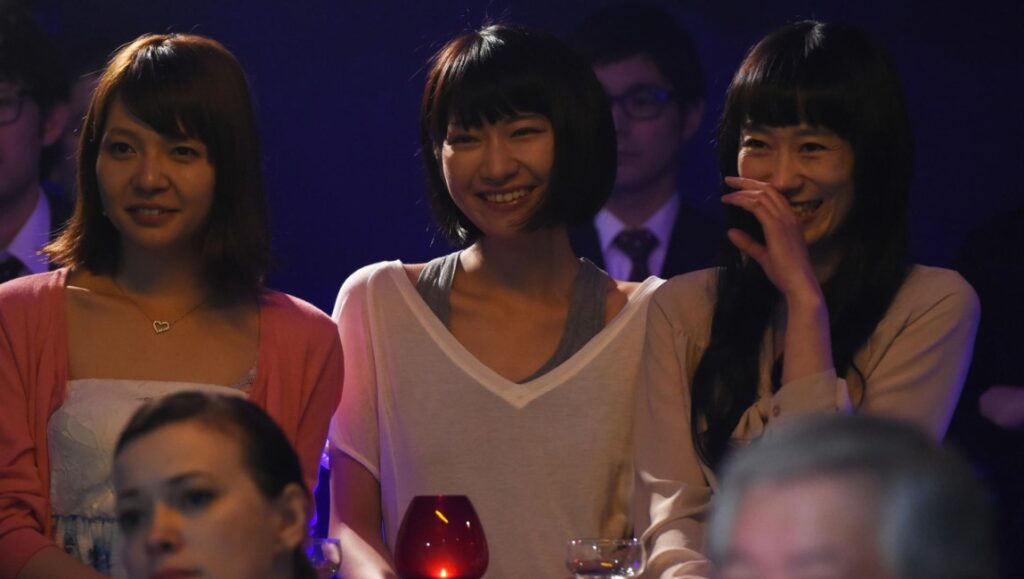 Dawn of the Felines | Kazuya Shiraichi Dawn of the Felines scene: Women smiling in a crowd. Kazuya Shiraishi film.