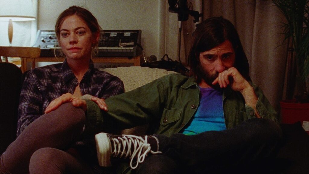 Golden Exits | Alex Ross Perry Still from Golden Exits by Alex Ross Perry, featuring two people sitting on a couch.