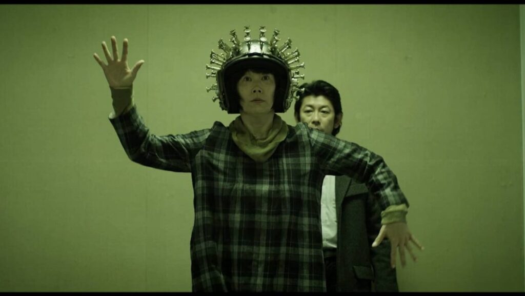 SABU's Happiness film still. A person wears a helmet with spikes, arms outstretched, with another person behind them.