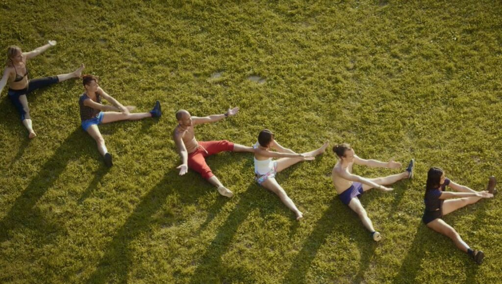 Happiness Academy artwork: People doing stretches on grass. Alain Della Negra & Kaori Kinoshita art installation.