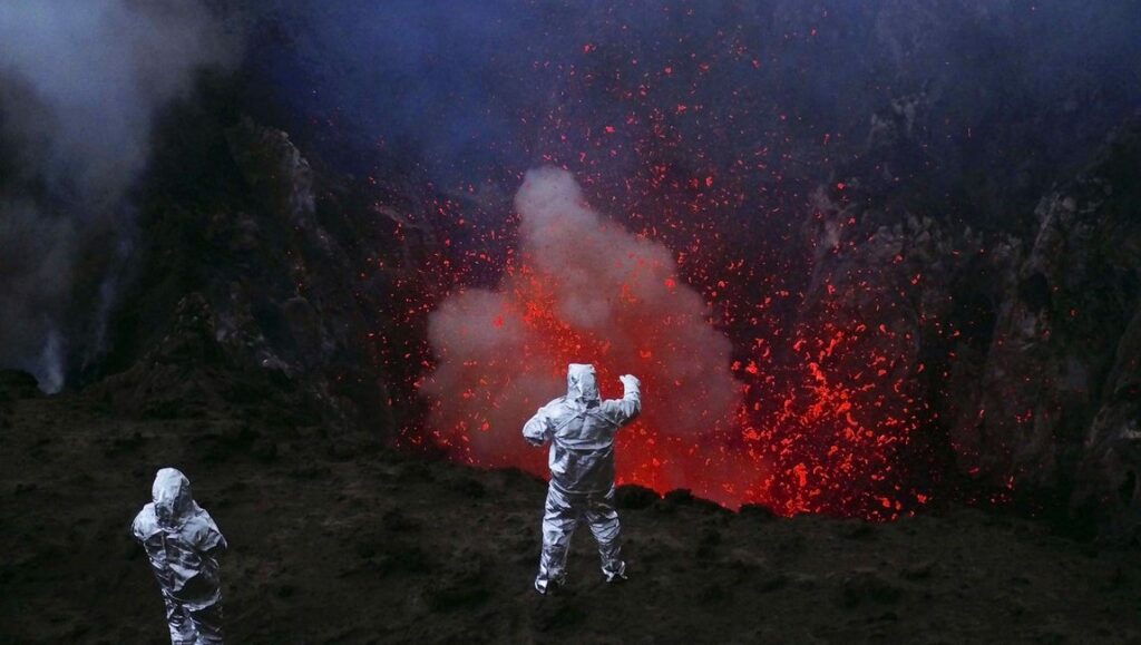 Werner Herzog's Into the Inferno: Scientists in protective suits observe an erupting volcano with flowing lava.
