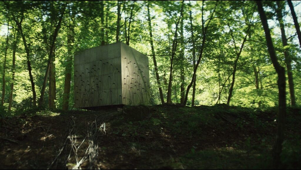 Lapsis movie still. Concrete cube with wires in forest. Sci-fi, Noah Hutton film.