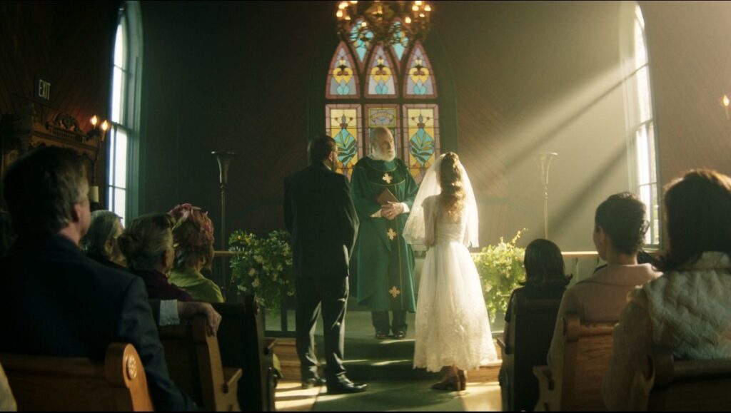 The Mortuary Collection | Ryan Spindell The Mortuary Collection movie scene: Bride and groom at a church wedding ceremony, with a priest and wedding guests.